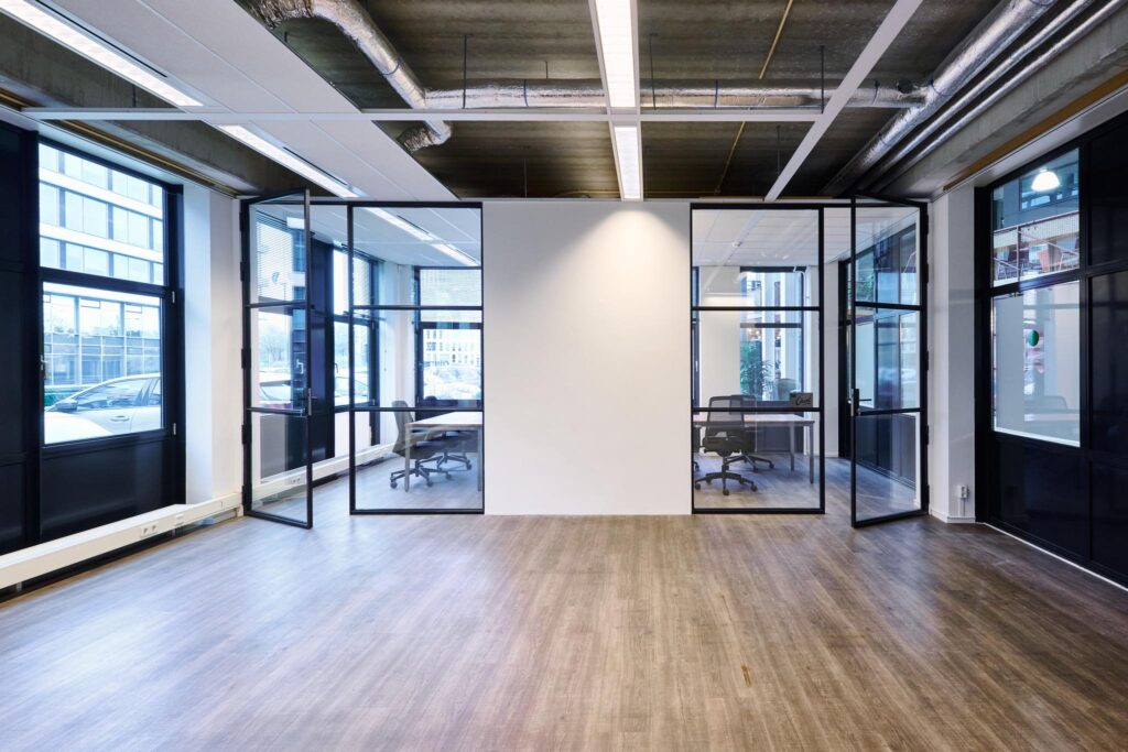 Moderne kantoorruimte aan het John M. Keynesplein met glazen vergaderruimtes en industriële plafonddetails.